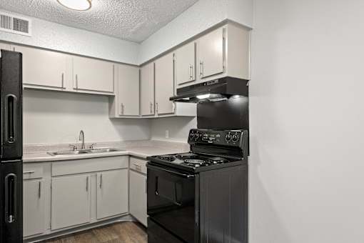 A black stove in a kitchen with white cabinets.