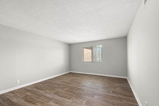A room with wooden flooring and a window with blinds.