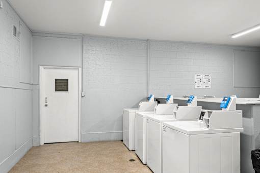 A white room with a door and a row of washing machines.