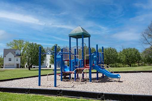 A playground with a blue slide and a green roofed structure.