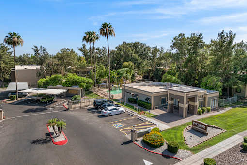 A parking lot with a building and palm trees in the background.