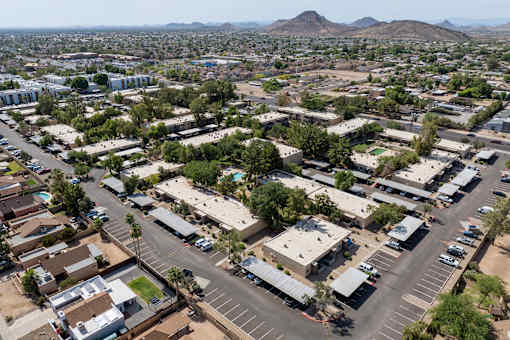 A large parking lot is surrounded by buildings and trees.