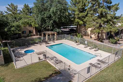 A pool surrounded by a fence and trees.