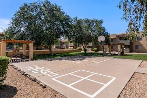 A basketball court is located in a courtyard surrounded by trees and buildings.