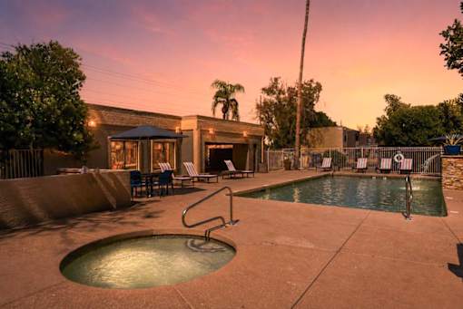 A pool with a hot tub and a building in the background.