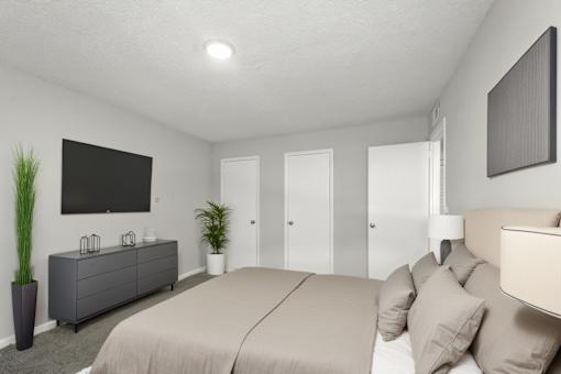 A bedroom with a large bed and a flat screen TV mounted on the wall.