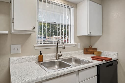 A kitchen with a window covered by a white curtain.