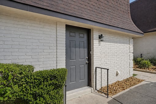 A grey door is on a white brick house.