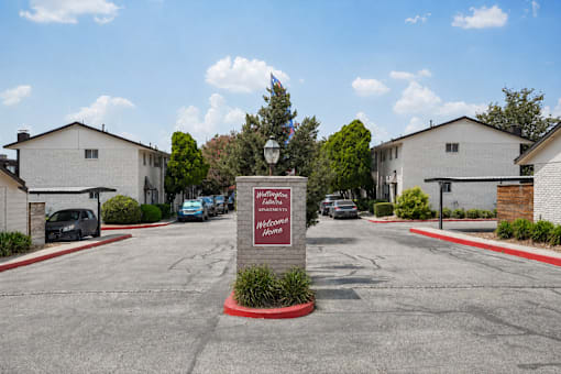 A sign in front of a building that says "Welcome to the Woodlands Apartments".