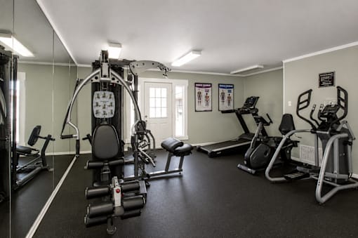 A gym with a variety of equipment including a treadmill, weights, and a stationary bike.