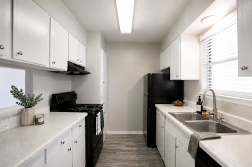 A kitchen with black appliances and white cabinets.