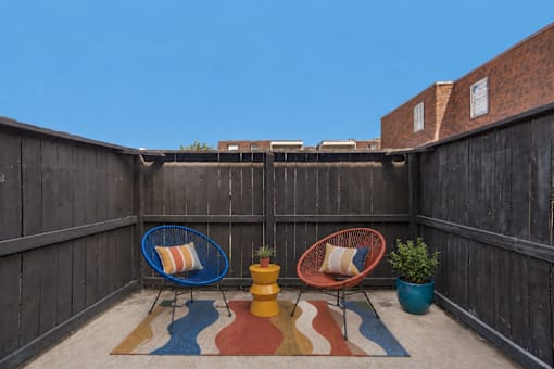 A small balcony with a blue chair, a yellow stool and a red chair.