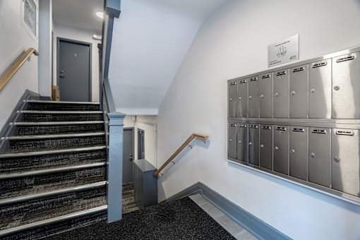 A staircase with a metal railing and a black carpeted floor.at 83-85 Silver Birch, California