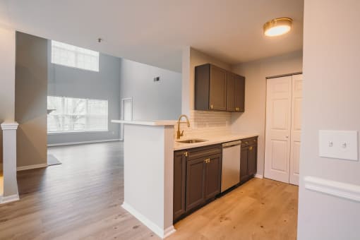 an empty kitchen with a white counter top and a door to a living room at Ardenwood Apartments, North Haven, CT, 06473
