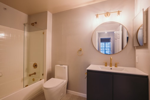 a bathroom with a toilet sink and a mirror at Ardenwood Apartments, North Haven, CT, 06473