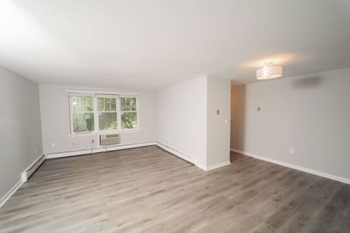 a living room with wood floors and white walls and a window  at Enclave West Hartford / Parc West, West Hartford