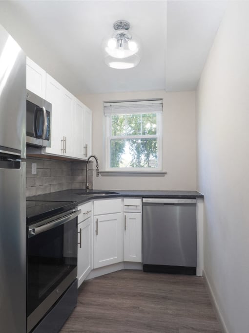 an empty kitchen with white cabinets and a black counter top  at Enclave West Hartford / Parc West, Connecticut
