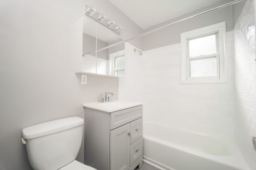 a white bathroom with a toilet and a tub at Encore 99, East Haven