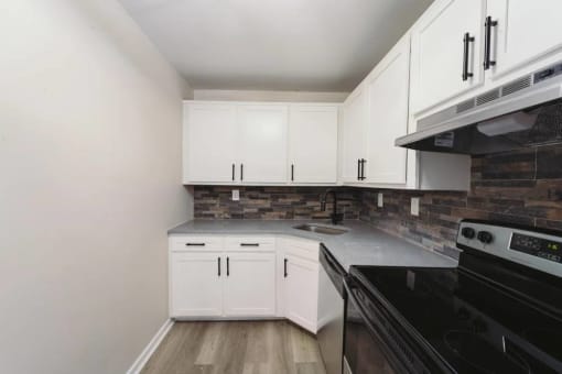 an empty kitchen with white cabinets and a black stove at Five High, West Hartford, 06119