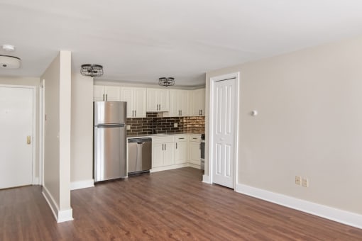 an empty living room with a kitchen with stainless steel appliances at Retro 511 Apartments, West Haven, CT 06516