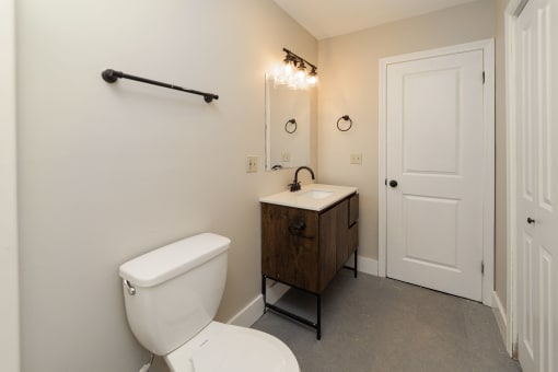 A white toilet sits next to a wooden cabinet in a bathroom at Retro 511 Apartments, Connecticut 06516