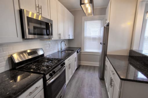 a kitchen with white cabinets and black counter tops at The Packard, West Hartford