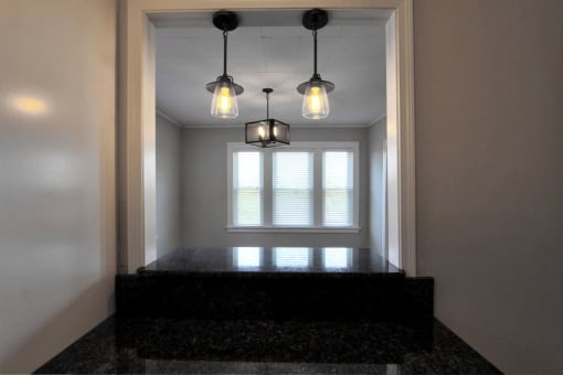 three lights hanging over a window in a room with a black counter at The Packard, West Hartford, 06119
