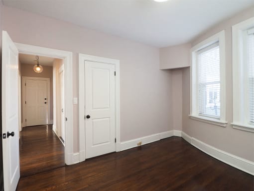 an empty living room with wood floors and a white door at The Packard, West Hartford, CT