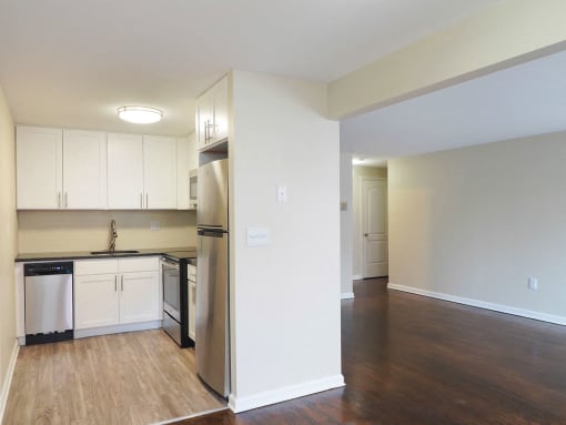an empty kitchen with white cabinets and a stainless steel refrigerator at The Packard, West Hartford