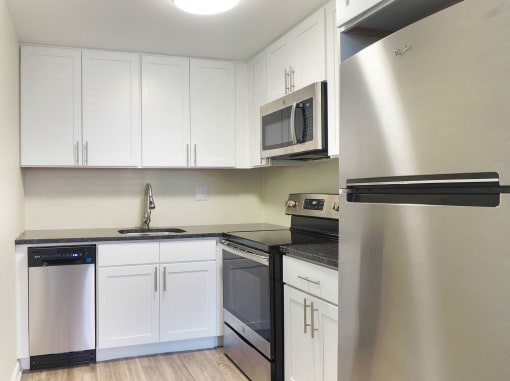 an empty kitchen with white cabinets and stainless steel appliances at The Packard, Connecticut, 06119