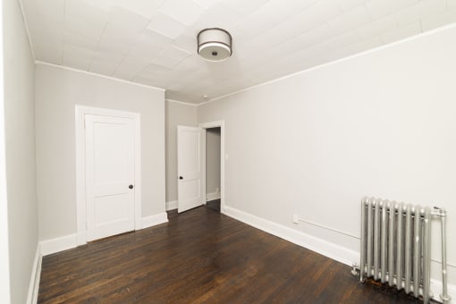 an empty room with a radiator and white walls at The Packard, West Hartford, CT, 06119