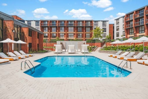 a pool with chairs and umbrellas in front of an apartment building at Up House, Connecticut