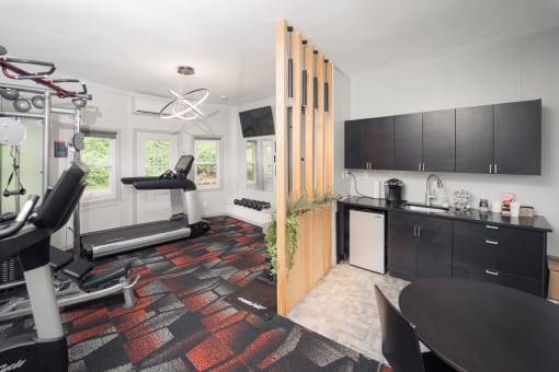 a gym with a reformer exercise machine and a kitchen with black cabinets at Woodbury, Woodbury, CT