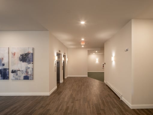 a hallway with white walls and wood floors and a painting on the wall