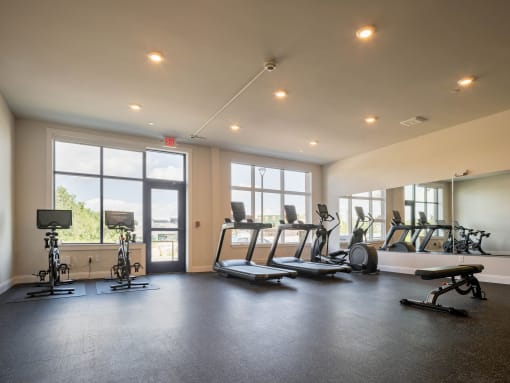 a gym with cardio equipment and windows in a building