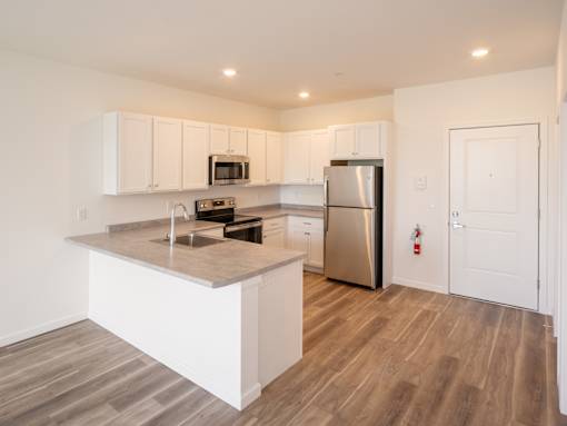 A kitchen with white cabinets and a wooden floor.