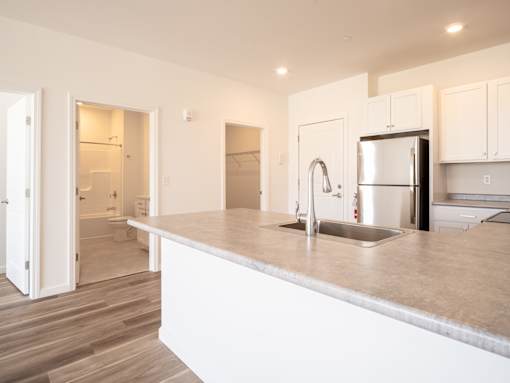 A kitchen with a white countertop and a stainless steel refrigerator.