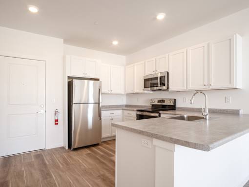 A kitchen with white cabinets and a stainless steel refrigerator.