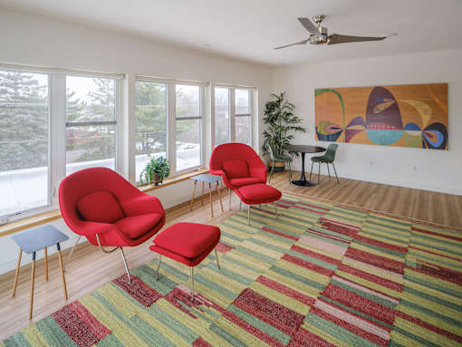 A room with red chairs and a painting on the wall.
