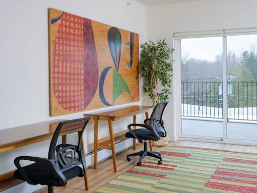 A room with a large painting on the wall and two chairs.