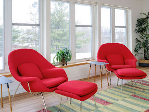 Three red chairs are placed in front of a window.