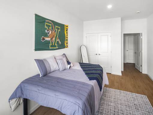 A bedroom with a bed, a mirror, and a flag hanging on the wall.