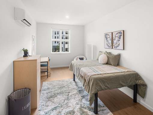 A bedroom with a bed, a dresser, and a window.