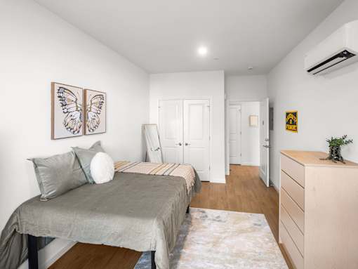 A bedroom with a bed, dresser, and a painting of butterflies on the wall.