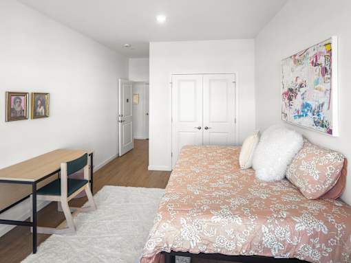 A bedroom with a bed, a desk, and a chair.