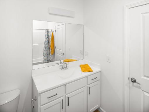 A white bathroom with a sink, mirror, and towel.