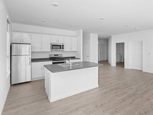 A modern kitchen with a refrigerator, microwave, oven, and sink.