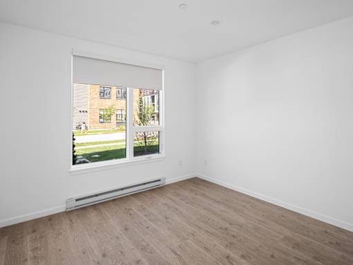 A room with a window showing a view of a building and greenery outside.