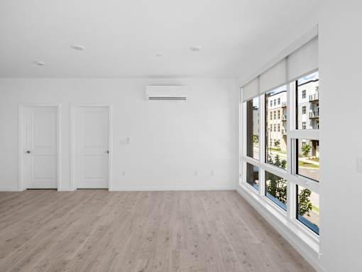 A room with a window showing a view of a street and buildings outside.