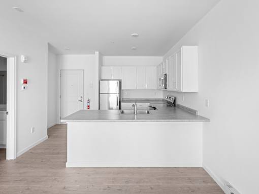 A kitchen with white cabinets and a wooden floor.